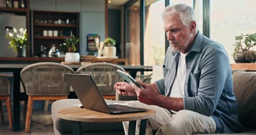 Senior Man Using Tablet and Laptop at Home
