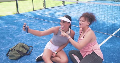 Mulheres afro-americanas na quadra azul, mulher deixada estendendo o smartphone, tirando selfies e revisando