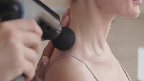 Therapist Using Massage Gun on Muscles of Patient