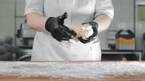 Person Kneading Dough on Flour-Covered Table