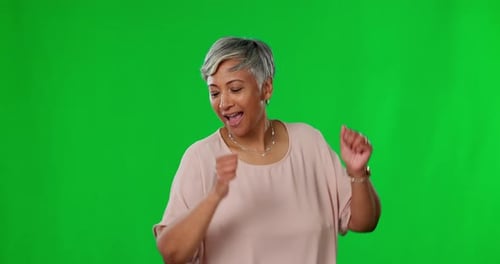 Dance, green screen and happy mature woman dancing in celebration after winning isolated in a studio