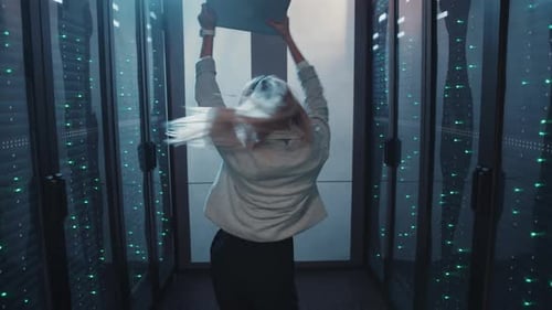 Excited woman dancing with laptop in server room
