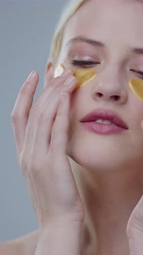 Woman Applies Golden Cosmetic Eye Patches