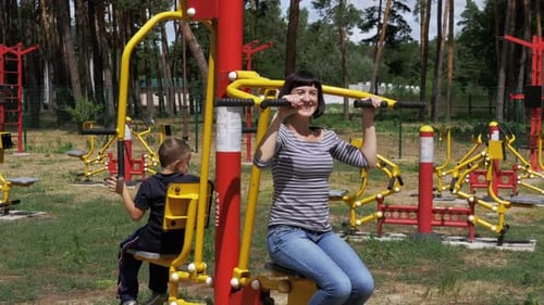 Mom and Son on Street Exercise Machines Go in for Sports