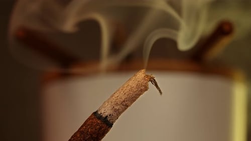 Macro shot of Incense sticks smoldering with puffs of smoke