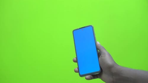 Hand Holding Smartphone with Blue Screen on Green