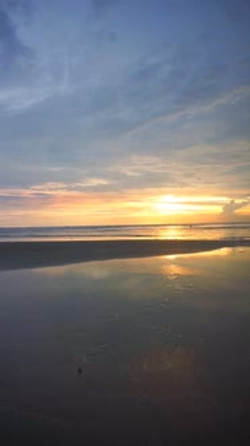 vertical video of beautiful views of the sunset on the beach with small waves, natural panoramas