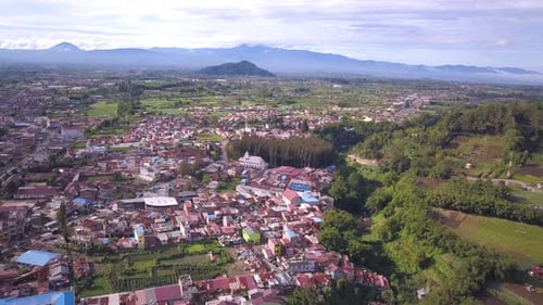 Panning aerial shot of a small village in Asia with mountains view, vegetable farm, and houses locat