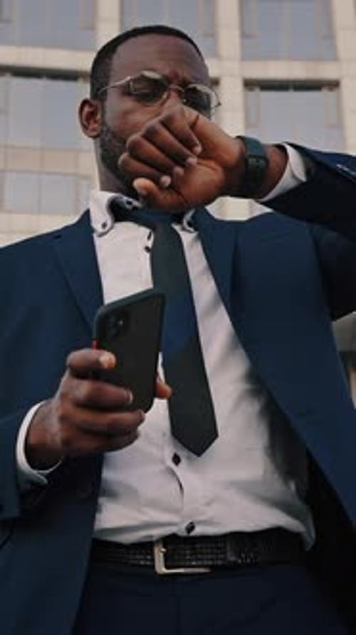 Man in Suit Checks Phone and Watch in City