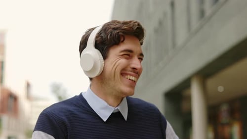 Fröhlicher Geschäftsmann mit kabellosen Kopfhörern, der draußen Musik hört und tanzt