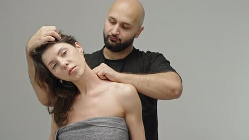 Therapist Performing Manual Neck Massage and Cervical Mobilization on a Client Tilting the Head to