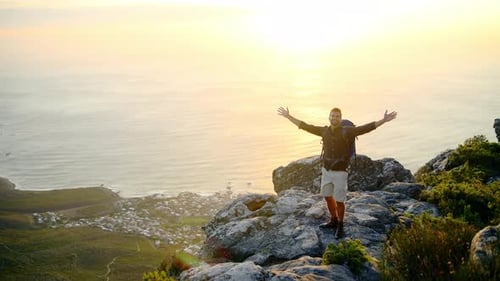 Arms raised, hiking or happy man in celebration on mountain peak in nature adventure walking