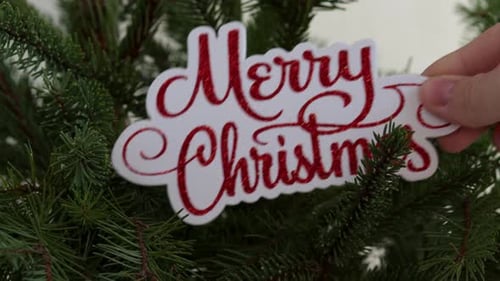 Decorating Christmas Tree with Glittery Merry Christmas Ornament
