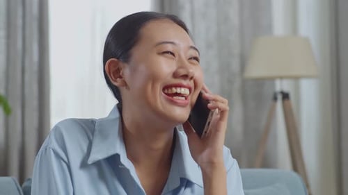 Close Up Of Asian Woman Talking On Smartphone While Sitting On Sofa In The Living Room