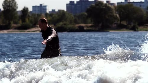 Man Wakeboarding on Choppy Water in City Setting