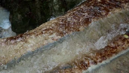 relaxing waterfall in a mountain stream with little canyon on the background, running water close up