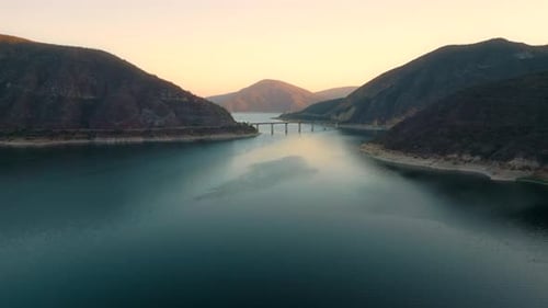 Aerial drone flying over a lake, water dam, with mountains at sunrise. Beautifull dreamy landscape