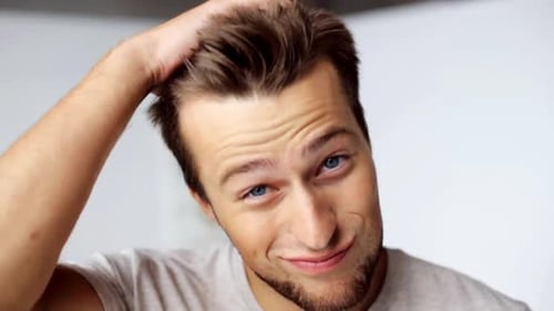 Handsome man smiles and runs hand through hair