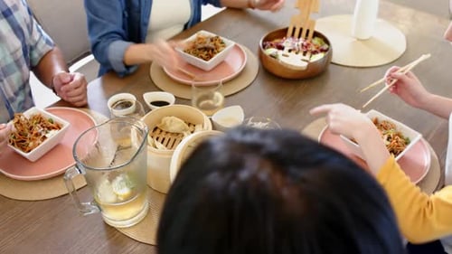 Friends Enjoying Asian Food Together at Dining Table