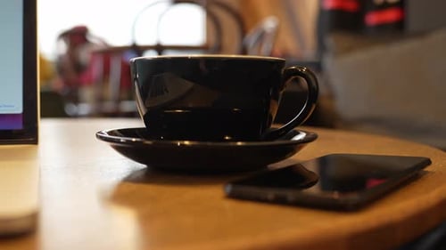 Tasse à café noire sur un bureau, gros plan à main levée