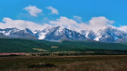 White Clouds Passing Over Majestic Snow Capped Mountain Range on a Bright Sunny Day Panoramic