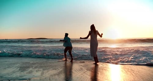 Couple, beach and waves in ocean with playing for vacation, holiday and sunset date in Greece