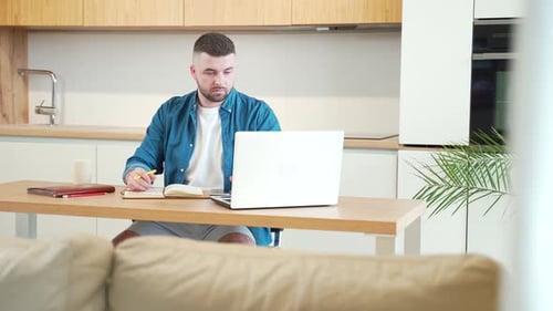 Man Working from Home Using Laptop and Notebook