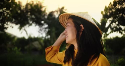 Smiling Woman in Traditional Hat Enjoys Golden Sunset