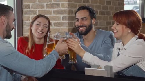 Des amis joyeux qui tintent des verres à bière au pub