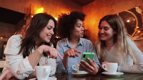 Three Young Women Enjoying Social Media in Cafe