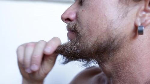 Man touches his beard on white background