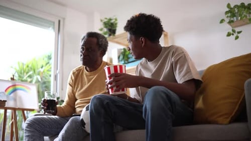 Grandfather and Teen Watching TV on Couch