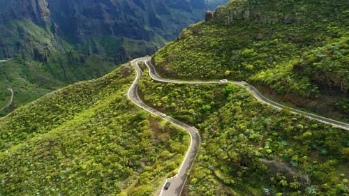 Cars Driving on New Asphalt Winding Road in Spring Green Mountain Landscape