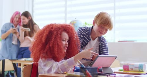 Side View of Boys and Red Haired Girl Talking and Using Digital Tablet During Break in School Happy