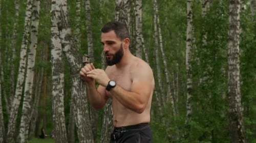 Fighter Training Kicks and Punches in Forest