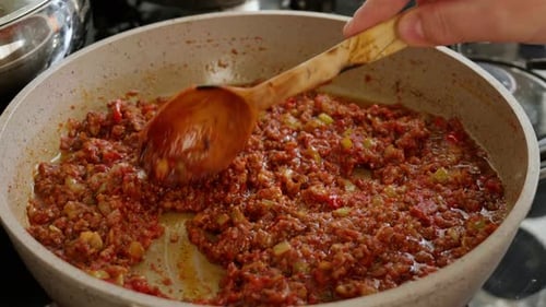 Cooking Bolognese Sauce in Pan with Wooden Spoon
