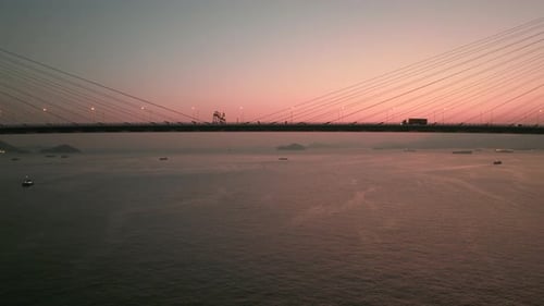 Verkehr auf einer hohen Hängebrücke mit einem wunderschönen roten Sonnenuntergang. Kippschuss beim Heben einer Drohne