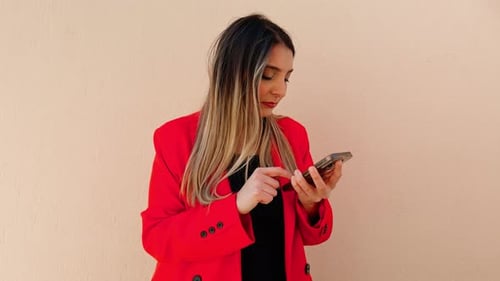 Woman Using Smartphone in Front of Neutral Wall
