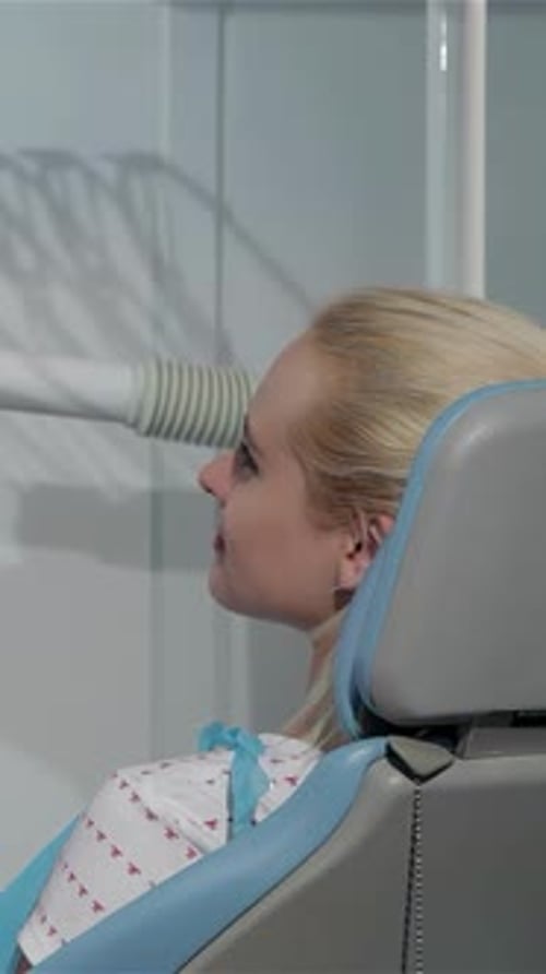 Une dentiste souriante examine la bouche du patient dans un cabinet dentaire lumineux