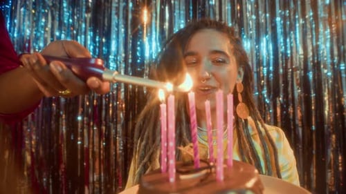 Woman Smiles as Candles are Lit on Birthday Cake