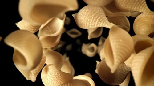 Uncooked Pasta Shells Floating Against Black Background