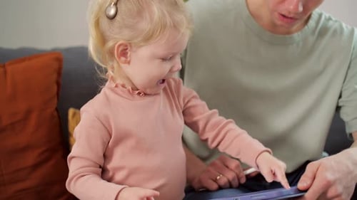 A Child with Cochlear Implants Plays with a Tablet Computer with His Father