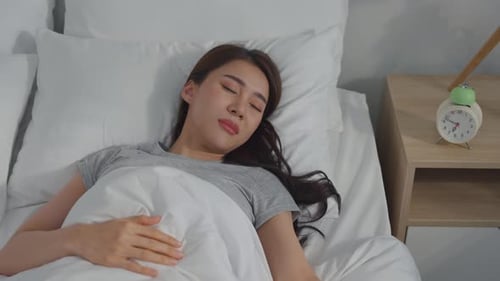 Asian beautiful tired young woman turn off an alarm clock in morning.