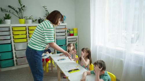 Teacher Helping Young Students in Classroom