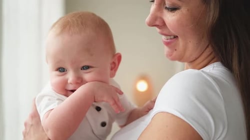 Smiling Baby Held by Mother Indoors
