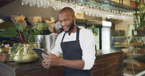 Coffee shop owner, manager or waiter checking tablet for online orders, social media marketing