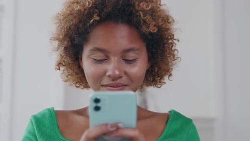 Young Woman Smiling Using Mobile Phone Indoors