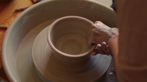 Hands of Artisan Shaping Clay into Bowl on Pottery Wheel in Ceramics Studio