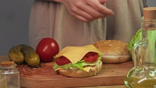 Der Küchenchef vervollständigt die Zubereitung des Burgers auf einem Holzschneidebrett, umgeben von all den