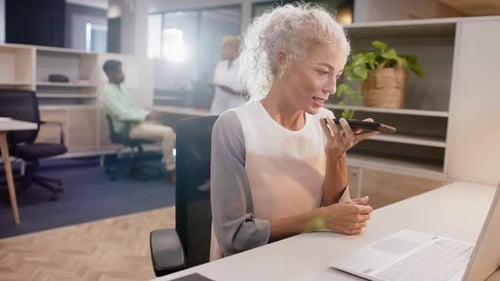 Working in office, woman using smartphone and laptop, multitasking at desk